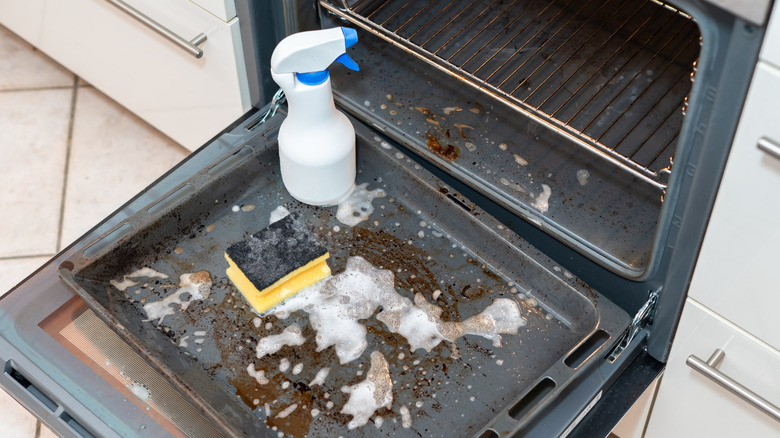 A messy oven being cleaned with soap