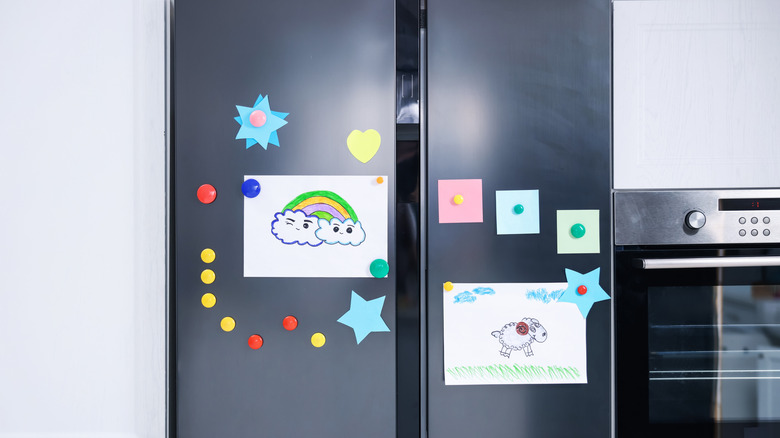 refrigerator with child's drawings and magnets on it