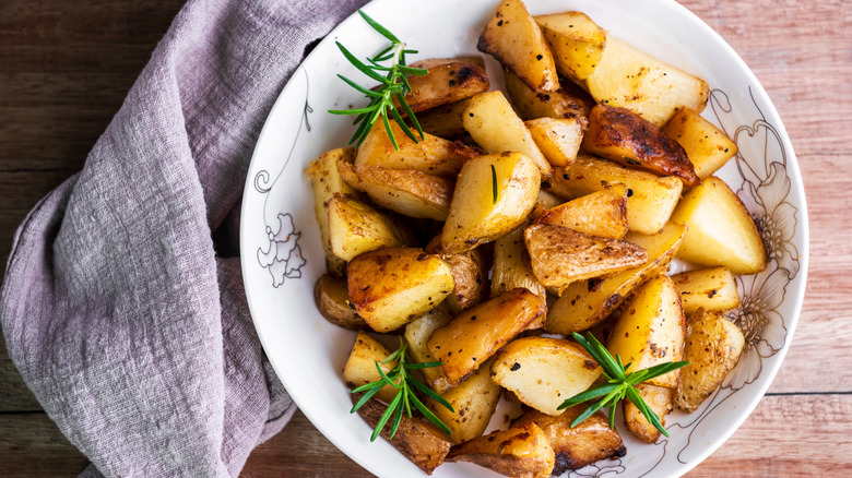 potatoes in white dish with rosemary sprigs