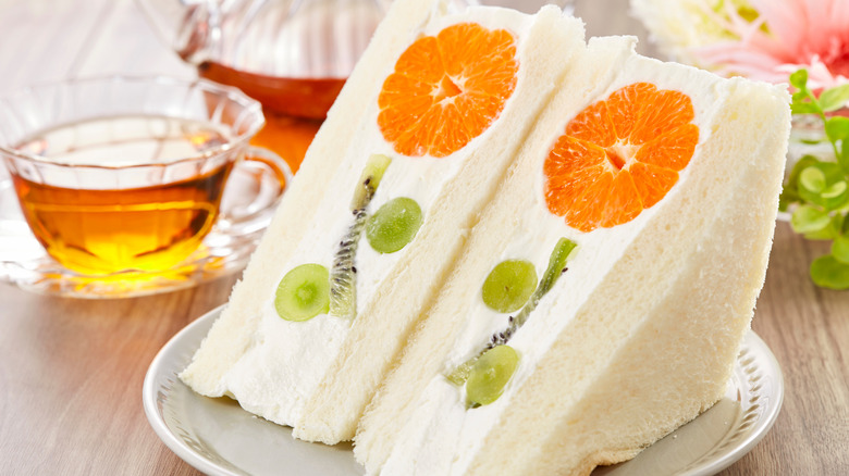 Two fruit sando halves with oranges, kiwi, and grapes forming a flower design