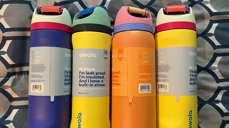 Four colorful Owala water bottles against a geometric background