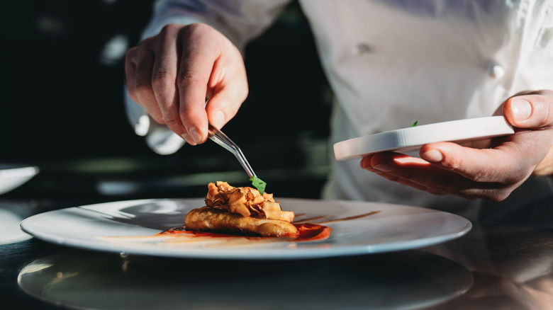 A chef plates microgreens with tweezers
