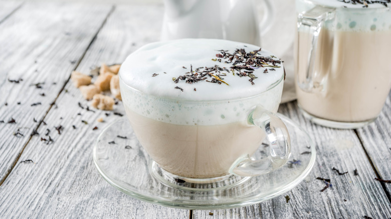 A cup of London fog latte with Earl Grey leaves scattered around