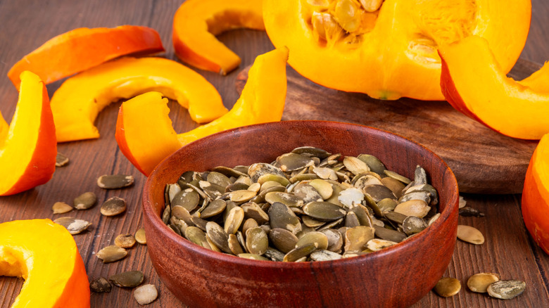 slices of fresh pumpkin surrounding a bowl of pumpkin seeds