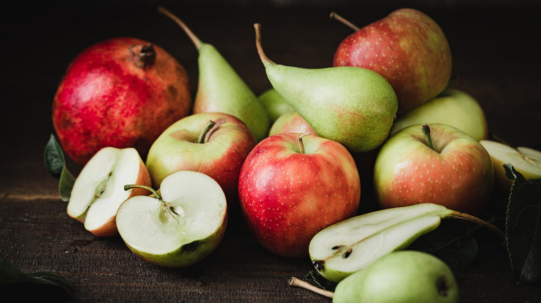 apples, pears, and pomegranates on a dark background