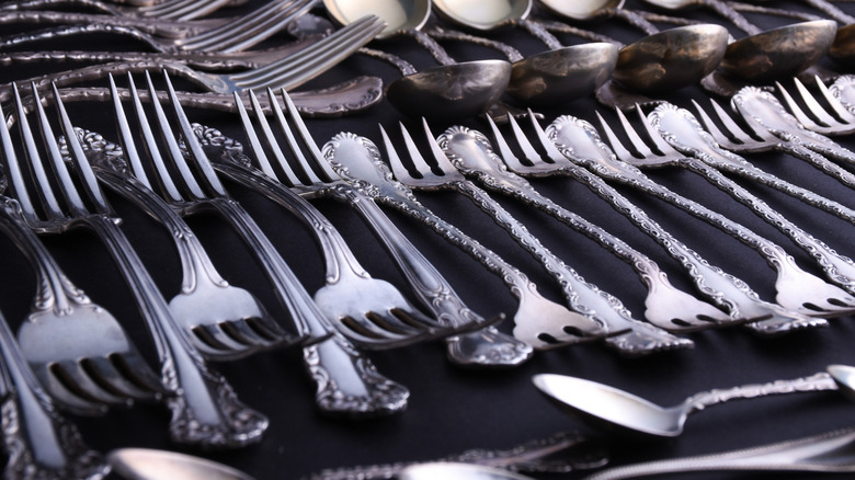A series of sterling silver forks laid out next to each other.