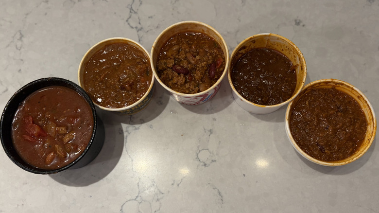 A lineup of chili from five restaurant chains on a marble countertop