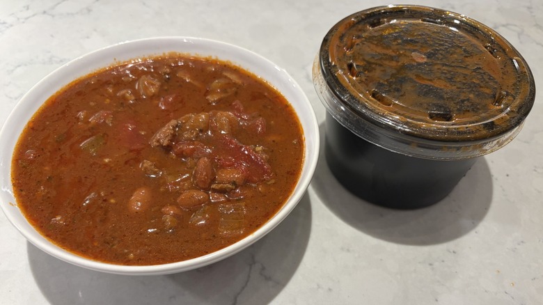 A bowl of chili from Quiznos next to its original container