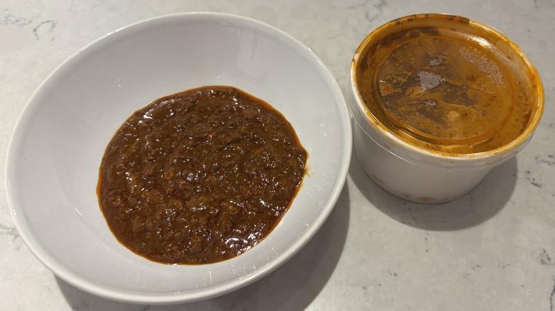 A bowl of Homestyle Chili next to its original container from Smashburger