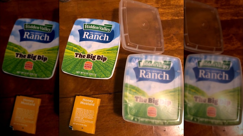 Two of Burger King's Hidden Valley Ranch "The Big Dip" sauce packets sitting on a wooden table