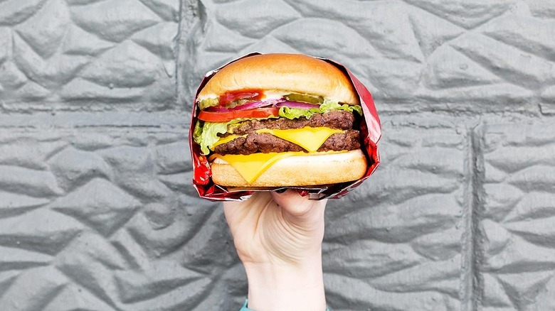 A person holding a Wendy's cheesburger