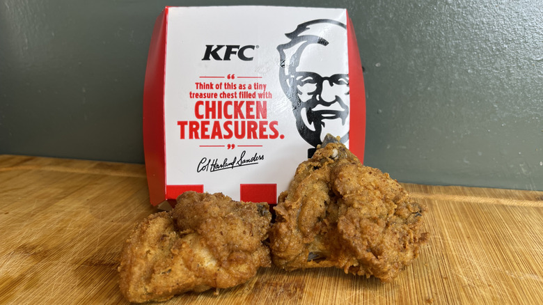 Two chicken wings from KFC propped up near the box