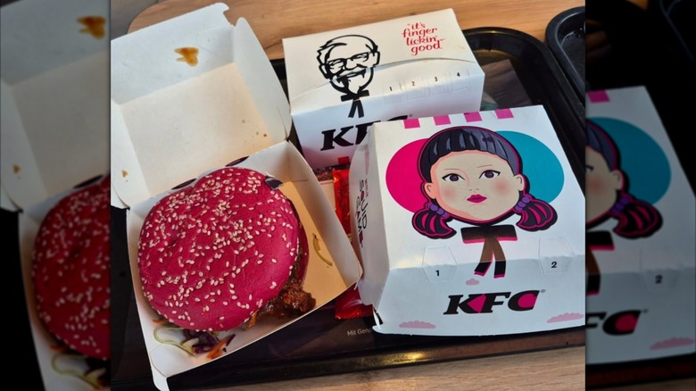 Squid game themed chicken sandwich next to squid game box on tray.