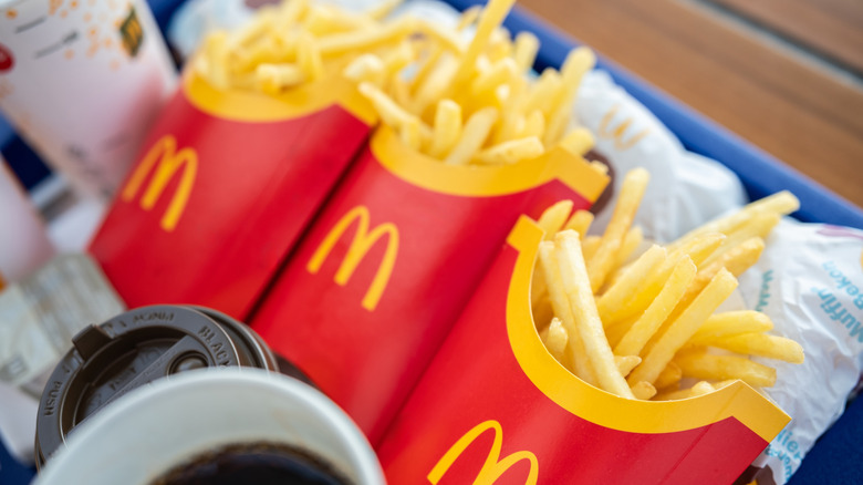 Three cartons of McDonald's fries on a tray with drinks