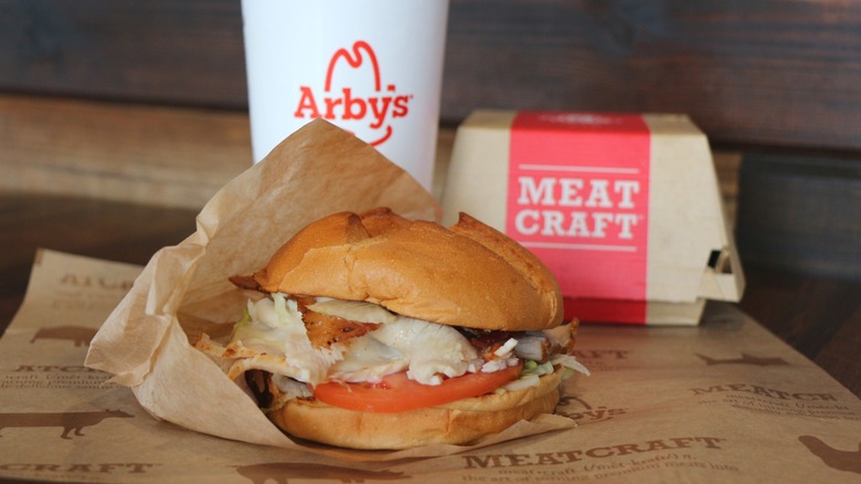 Arby's sandwich in front of a branded cup and to-go box