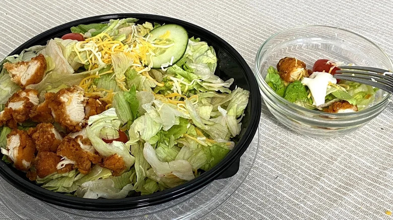 Bojangles' Chicken Supremes Salad in a takeout container with a bowl on the side