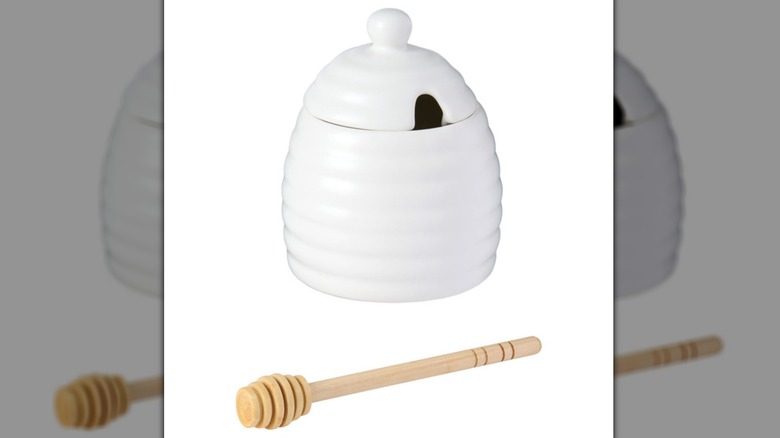 White ceramic honey pot with a wooden honey scoop.
