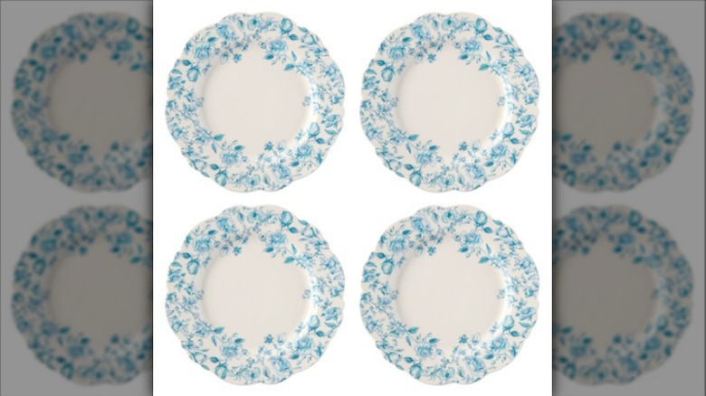 Four white plates with blue decorations and scalloped edges.