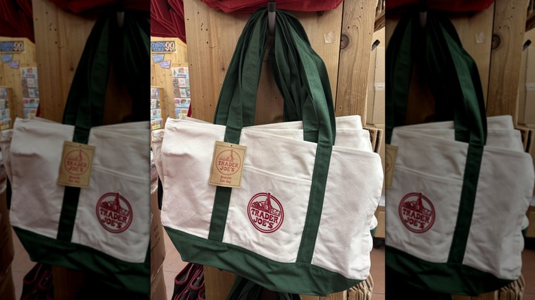 Green and cream tote bags hanging on the wall at Trader Joe's