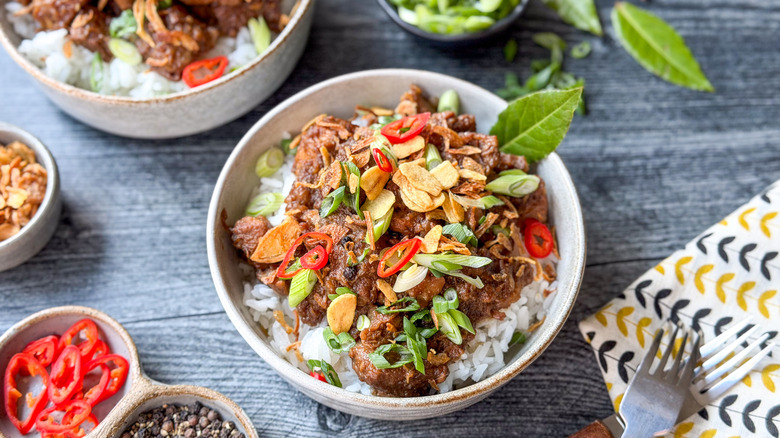 Filipino pork adobo over rice in serving bowls with garnishes
