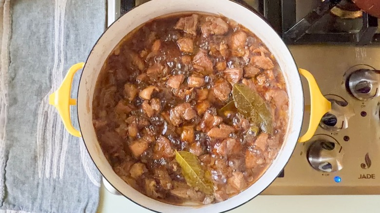 Filipino pork adobo simmering in yellow pot on stovetop