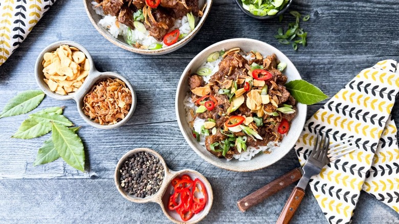 Filipino pork adobo over rice in serving dishes with garnishes