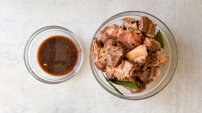 Raw marinated pork adobo in glass bowl with marinade