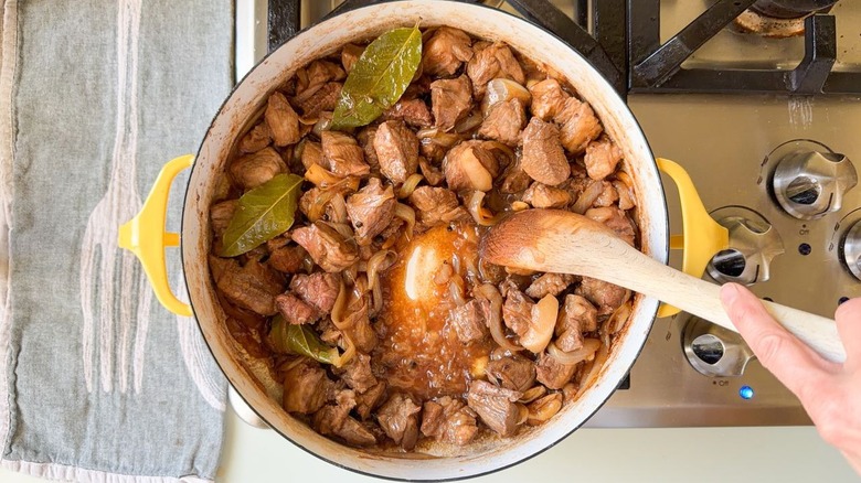 Cooking marinated pork shoulder in large pot on stovetop for adobo