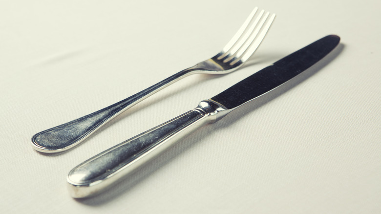 A fork and knife are pictured on a plain white background.