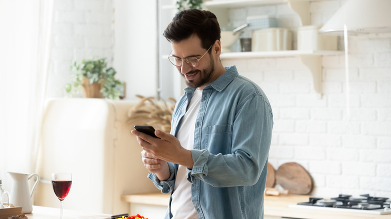 man using phone while cooking