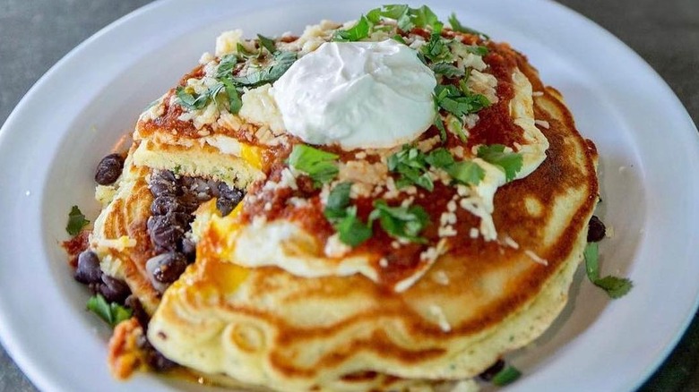 Plate of savory corn pancakes topped with cheese, herbs, and sour cream