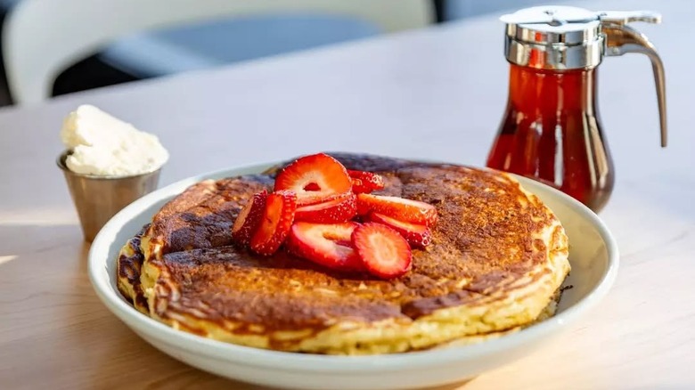 Stack of buttermilk pancakes topped with sliced strawberries