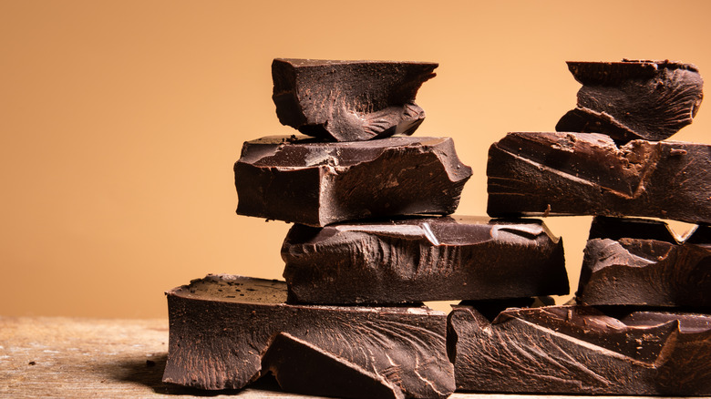 Heap of broken pieces of chocolate on a brown background