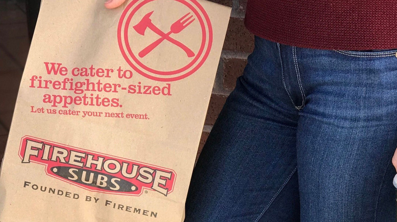 Person carrying bag of takeout from Firehouse Subs