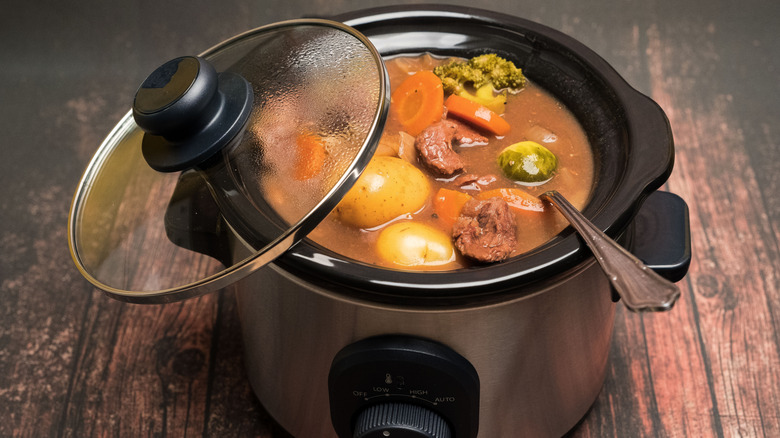Chicken soup inside a slow cooker with a spoon inside for serving.