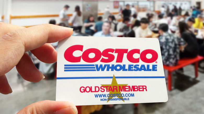 A person holding a Costco Gold Star membership card in a warehouse