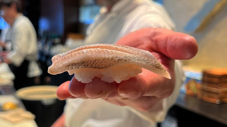 ayu nigiri from a sushi restaurant held by a sushi chef