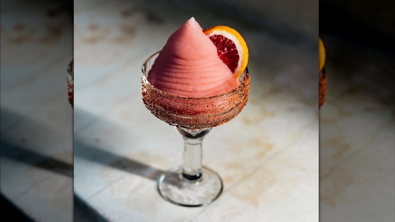 Oxomoxo's frozen drink is pink in a sugared glass with a citrus wheel garnish.