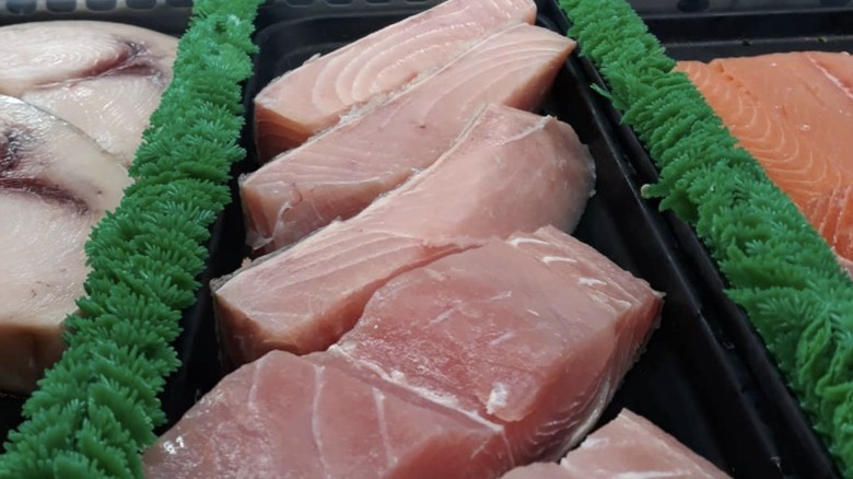 Three different kinds of fish cut and lined up on ice in rows at Wild Salmon Market in Seattle.