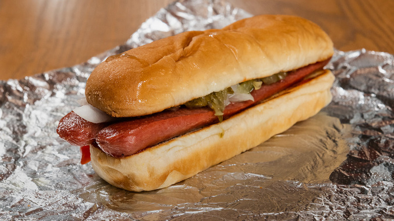 A Five Guys hot dog sitting on an aluminum foil wrapper