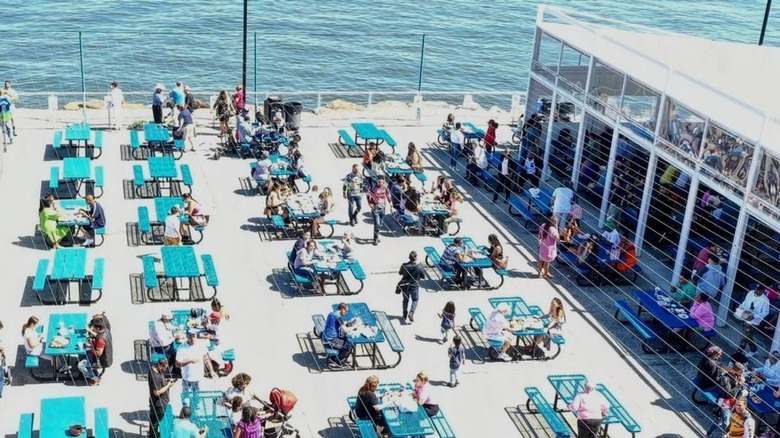 The waterfront patio at Johnny's reef is filled with people at picnic tables.