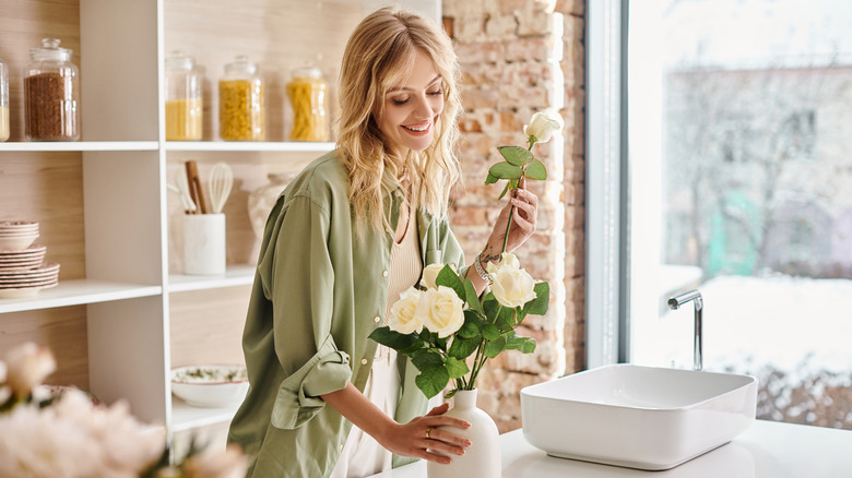 woman arranging flowers in kitchen