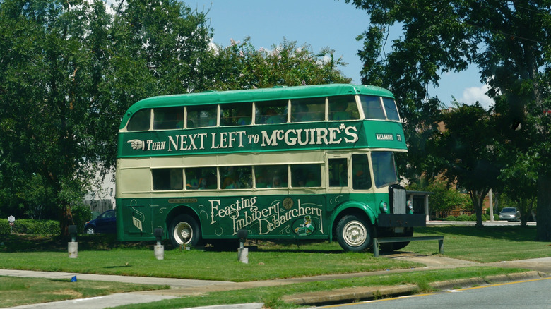 A double-decker green bus with the words: "Turn next left to McGuire's" on the side.