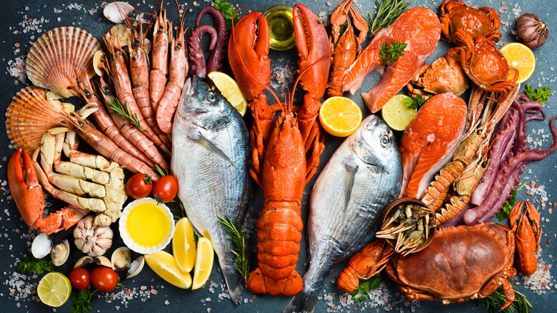 A huge display of various raw seafood and fish with lemon wedges and small bowls of clarified butter.
