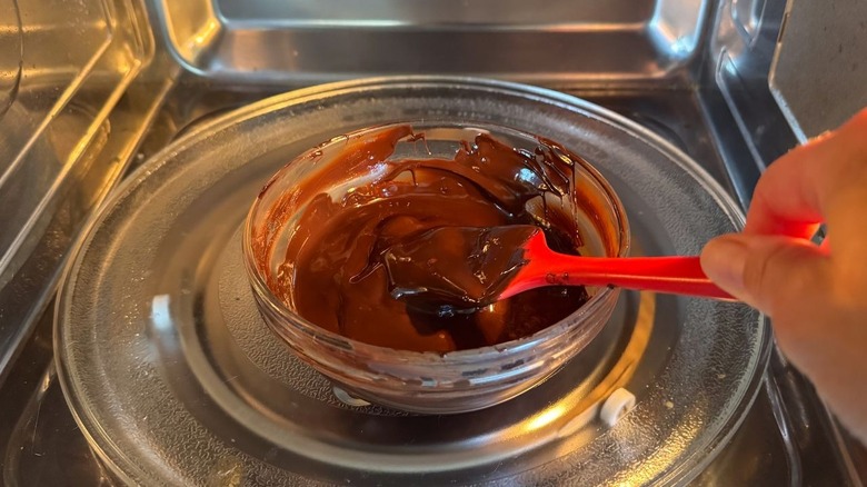 Stirring melted chocolate in glass bowl in microwave with rubber spatula