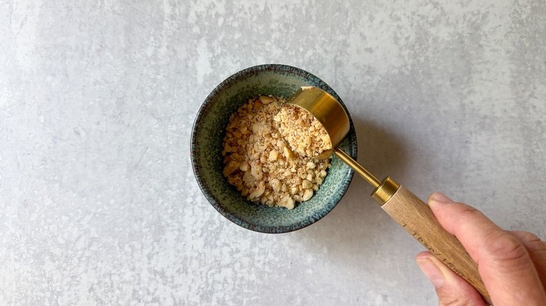 Adding chopped hazelnuts to small bowl with tablespoon