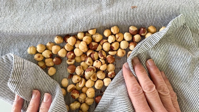 Rubbing toasted hazelnuts with a kitchen towel to remove skins