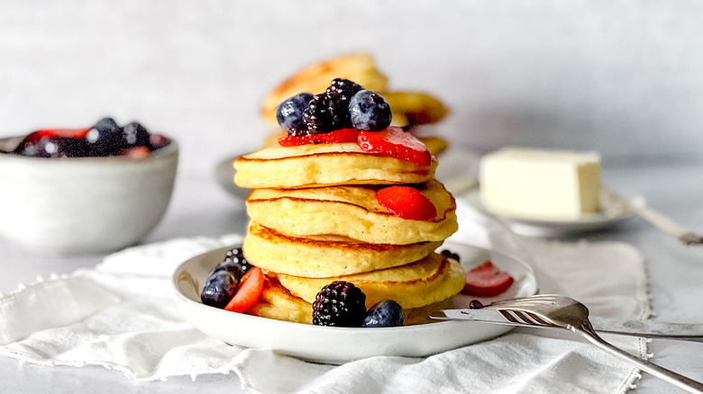 Fluffy lemon ricotta pancakes stacked on plate with berries