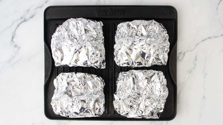 Four foil parcels on a grill pan