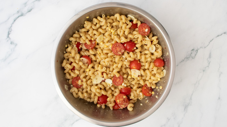 Tossed pasta, corn, and tomatoes in a large bowl